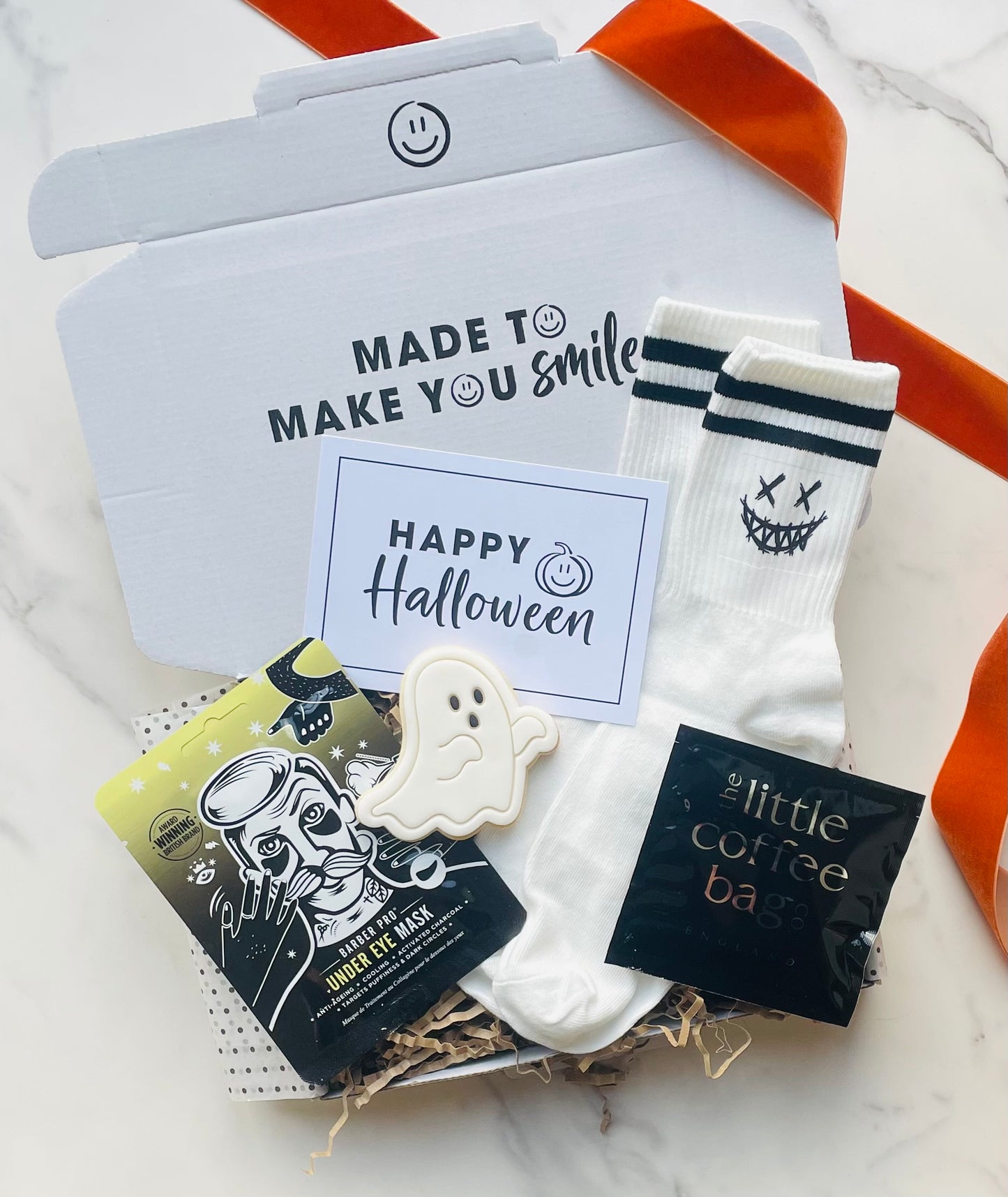 Halloween-themed items including socks, a face mask, and a card on a white surface.