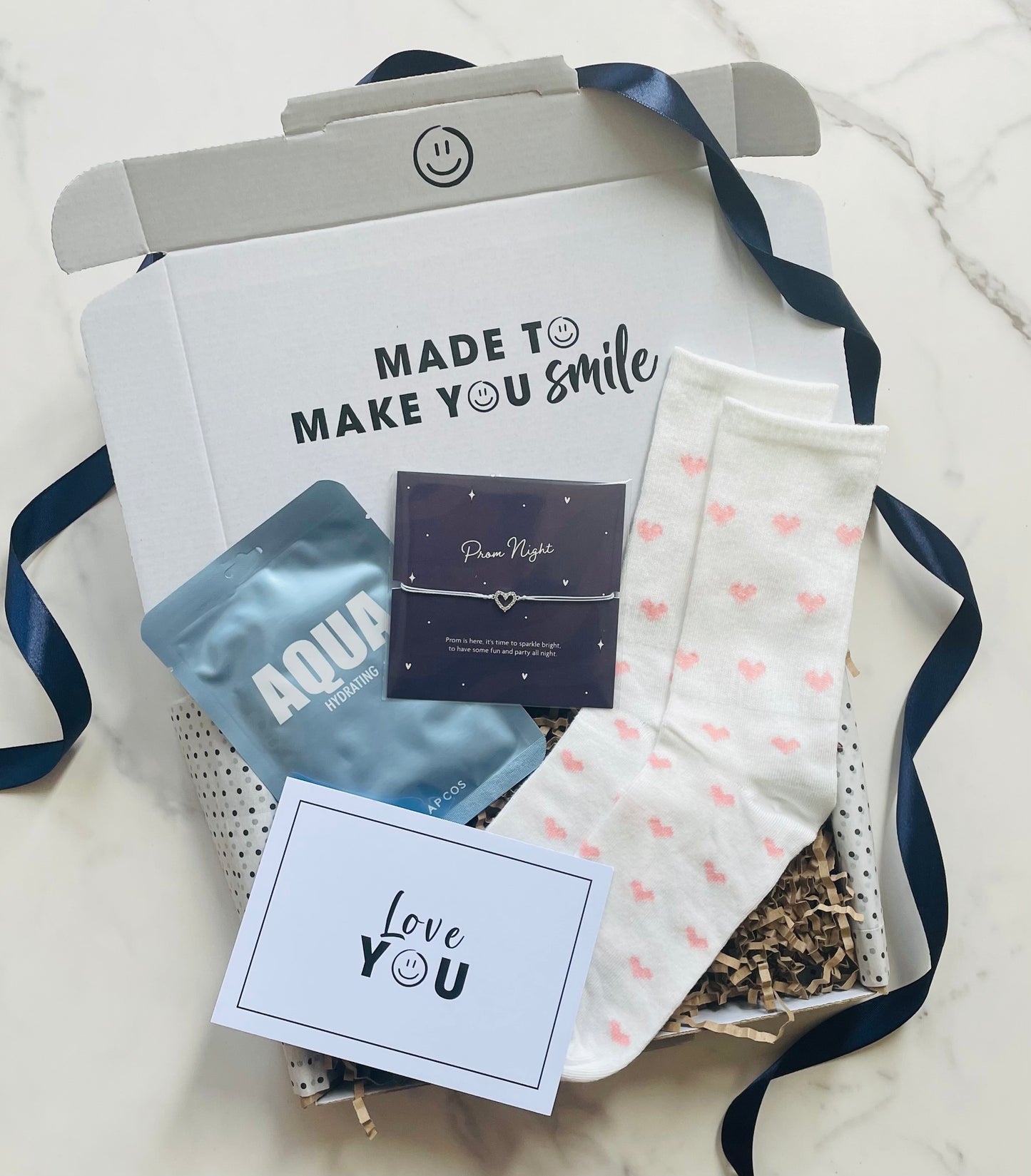 Gift set with a card, tea bags, and a small box on a marble surface