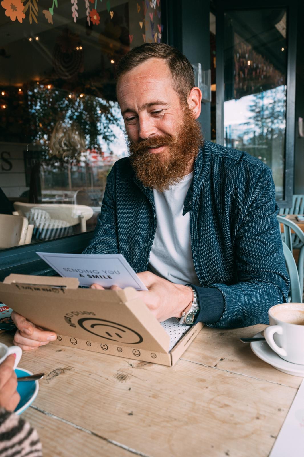 Man with a beard reading a Send a Smile gift box message