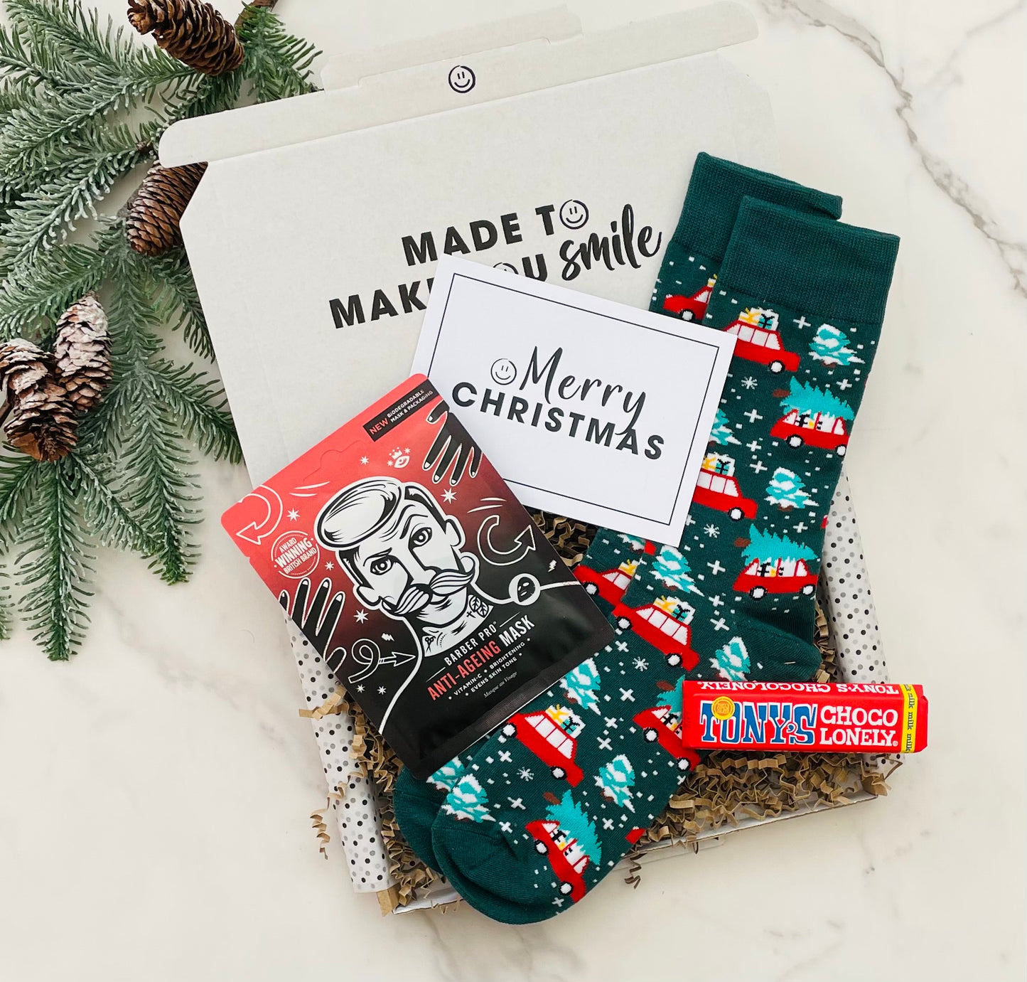 Men's Christmas Gift Box, including festive socks, Barber Pro Sheet mask, Tony's Chocolonely Milk Chocolate Bar and a Christmas Card. 