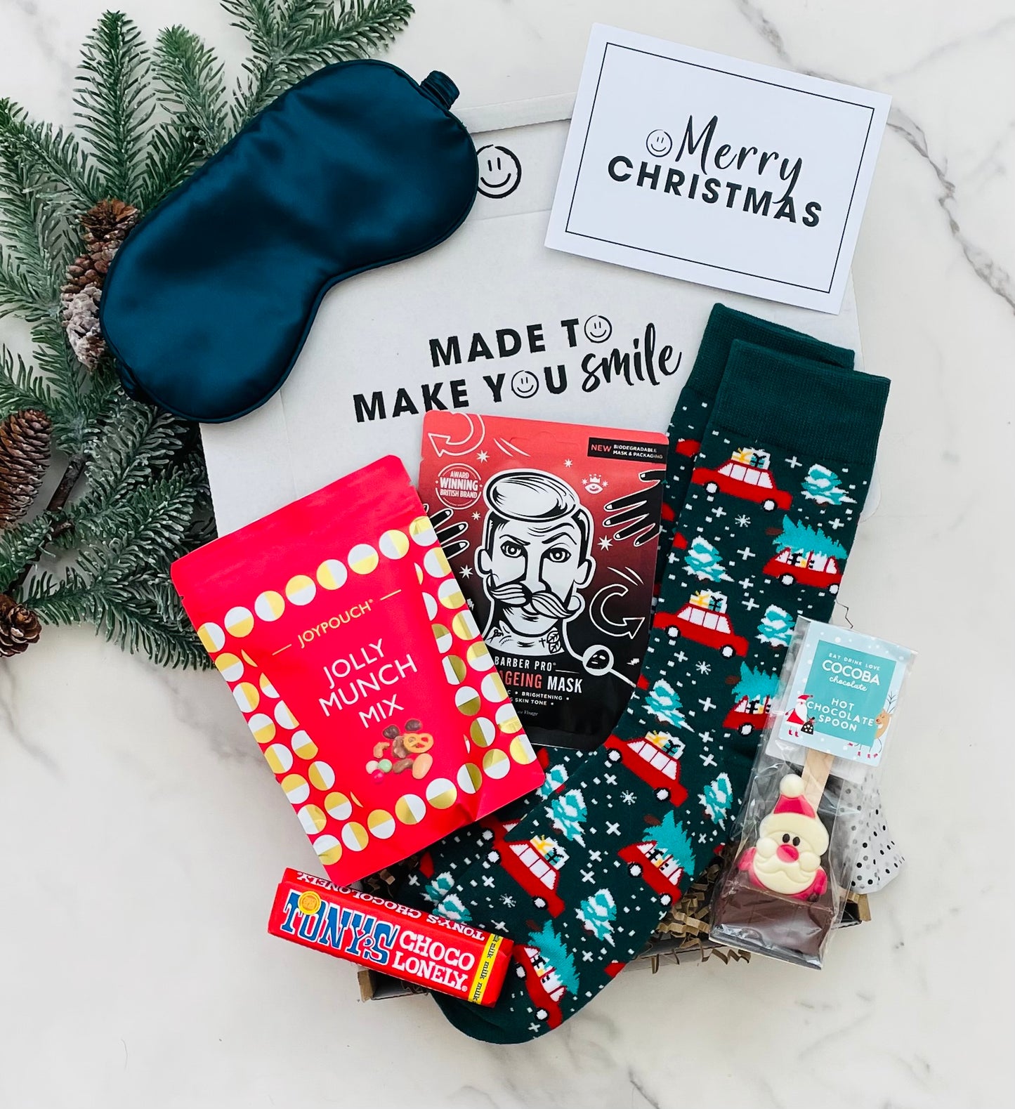 Men's Christmas gift box, including a sleep mask, snacks, hot chocolate and socks with a Merry Christmas card. 