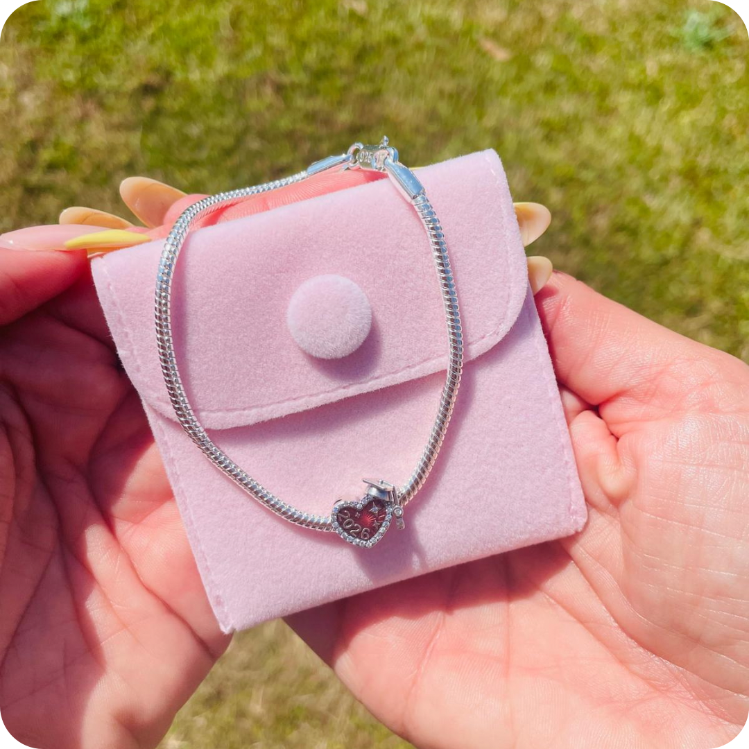 Silver charm bracelet with 2026 graduation charm on a cute pink jewellery pouch